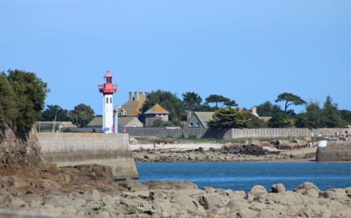 Phare rouge et blanc à L'Ermitage, Saint-Vaast-la-Hougue, avec fortifications côtières et plage de sable