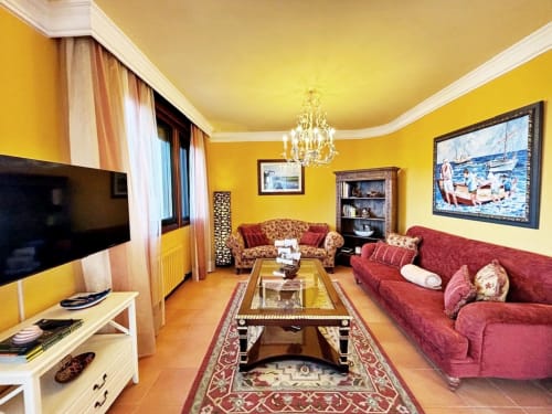 Elegante sala de estar amarilla con sofás rojos, lámpara de cristal y televisor de pantalla plana en villa Vila Arume, Baiona