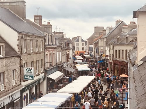 Marché animé de Saint-Vaast-la-Hougue avec ses tentes blanches et maisons en pierre historiques bordant la ruelle