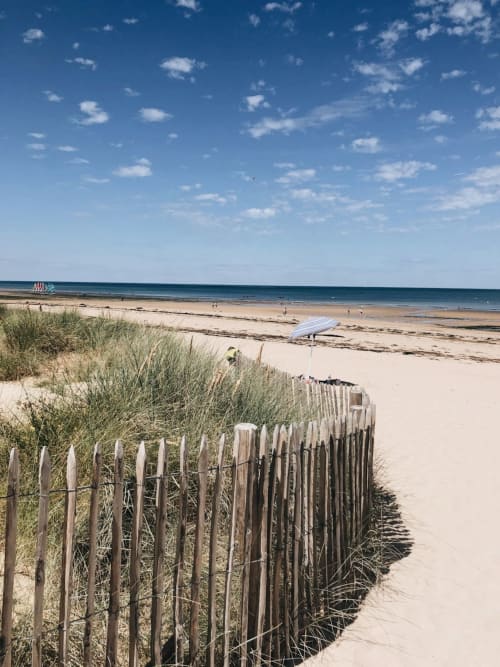 Wooden beach fence with dune grass overlooking sandy beach at L'Ermitage, Saint-Vaast-la-Hougue