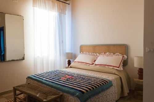Bright bedroom at Le Vajane B&B Torino di Sangro with wicker headboard, striped throw blanket, garden view through sheer