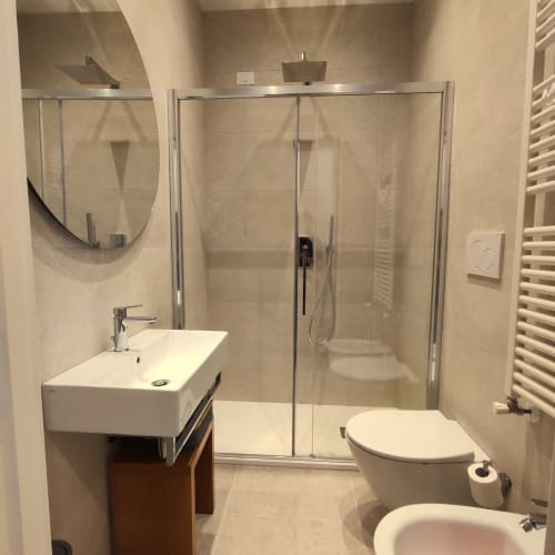 Modern bathroom in Stella CasaBono Junior Suite Superior, Sulmona, featuring glass shower enclosure, white sink, and toilet
