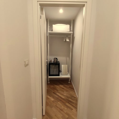Small hotel closet at Stella CasaBono with shelving, white linens, kettle, and wooden floor