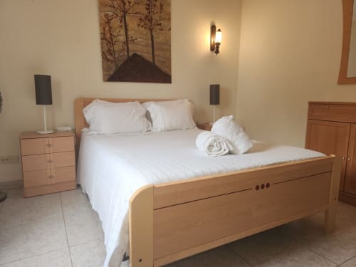 Quarto duplo ensolarado no albergue Sunny House em Lagos com cama de madeira, roupa de cama branca, mesas laterais e arte com vista para a cidade