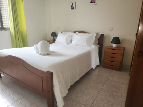 Chambre double du Sunny House hostel à Lagos avec deux lits à cadre bois, draps blancs, tables de nuit en bois et ventilateur