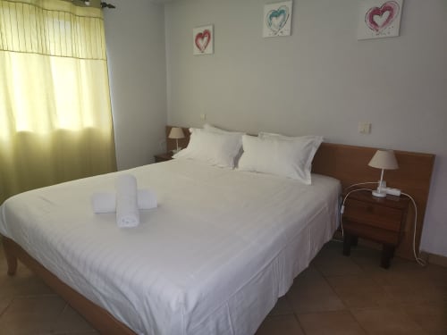 Lit double impeccable dans une chambre lumineuse de l'auberge Sunny House Lagos, décorée d'un motif cœur au mur et rideaux jaunes