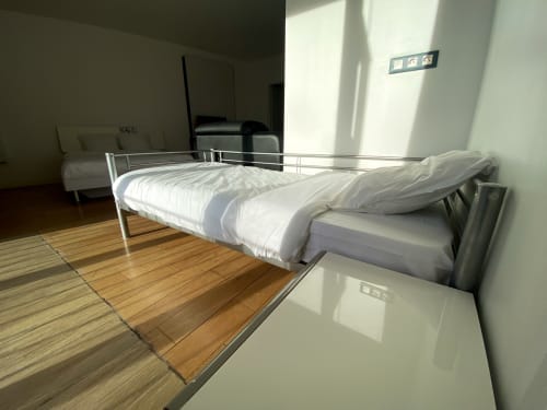 Chambre moderne à Chambre Pasteur à Montreuil : lit en métal, draps blancs, parquet, décoration minimaliste