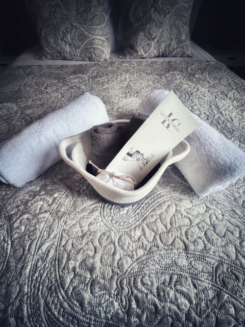 Panier d'aménités spa avec articles de toilette et serviettes sur la literie à motifs du Manoir Le Coutureau