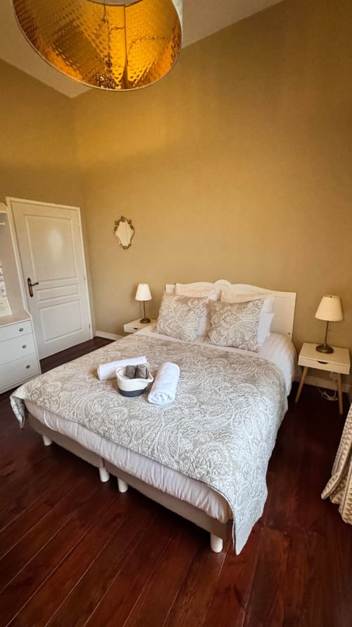 Chambre élégante au Manoir Le Coutureau avec lit queen-size, parure patterned, luminaire ambré et murs jaune chaud