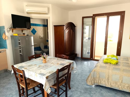 Luminoso monolocale a Leuca con tavolo da pranzo, angolo cottura, letti e porte con vista mare ai Panoramici Monolocali
