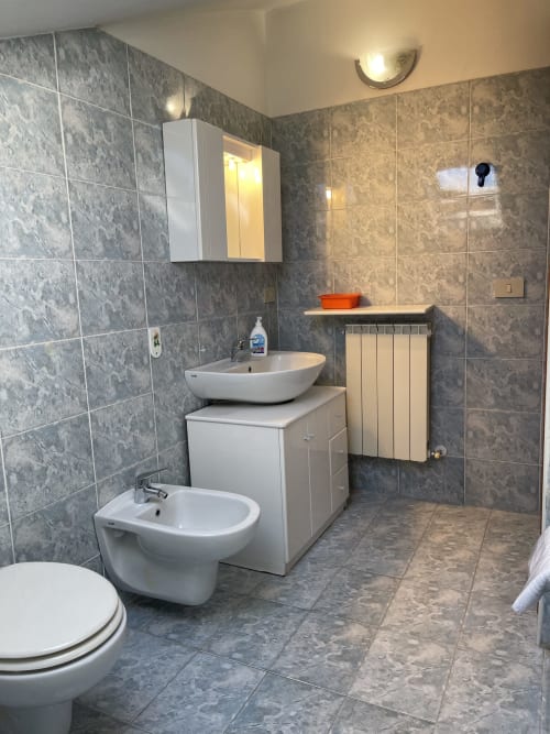 Moderno bagno degli Apartment Rigiariloo Home a San Giacomo degli Schiavoni con piastrelle grigie, sanitari bianchi e riscaldato