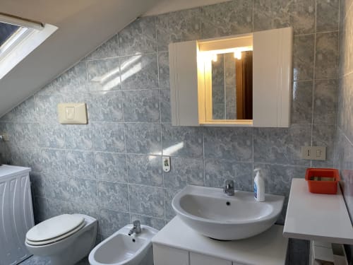Bagno moderno presso Rigiariloo Home Apartments con piastrelle in marmo, lavandino, toilette, bidet e specchiera illuminata