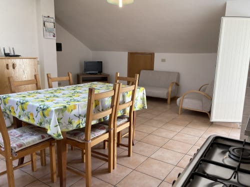 Accogliente appartamento a Rigiariloo Home Apartments con tavolo da pranzo, sedie in legno, divano e angolo cottura a San Giacomo degli