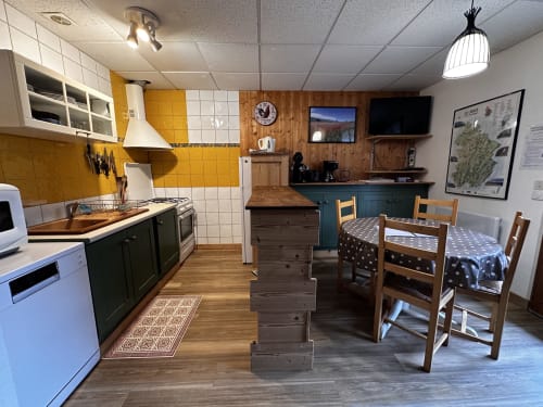 Spacieuse cuisine-séjour des Gîtes Des Planchettes avec dosseret en carrelage jaune, mobilier en bois et style rustique