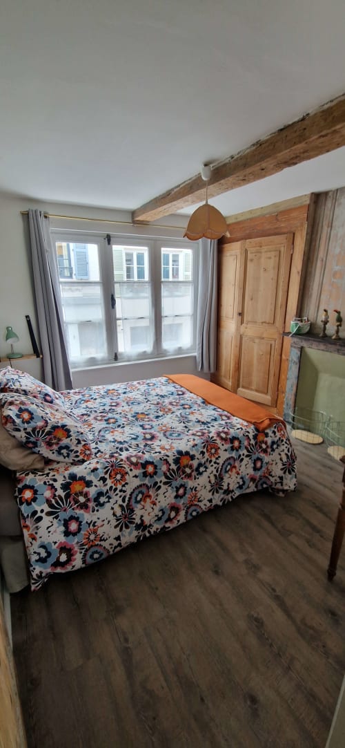 Chambre spacieuse aux poutres apparentes, literie fleurie, balcon vue mer et armoire en bois au cottage Vue D'ici