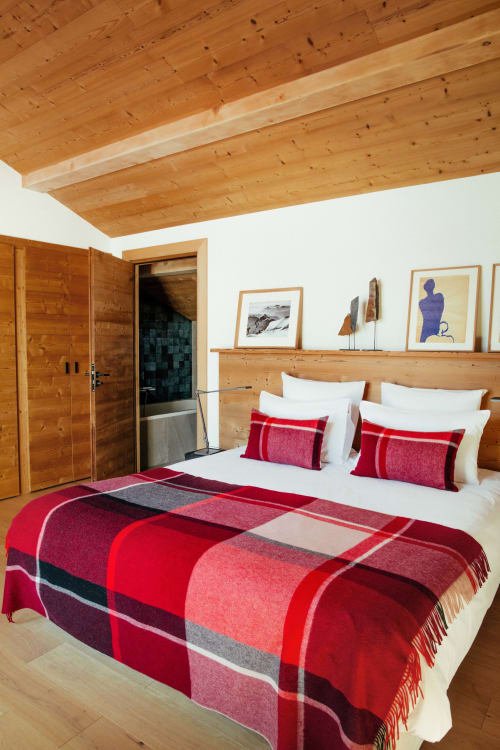 Chambre alpine moderne au Chalet Mont-Blanc à Chamonix avec poutres en bois, literie à carreaux rouges et tableaux encadrés