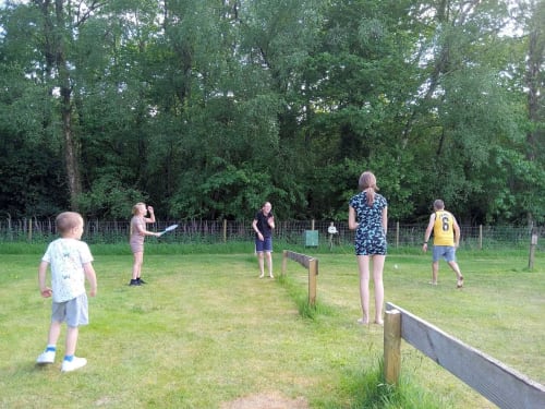 Children playing badminton at Postwood Gardens Campsite in Kentisbeare, surrounded by green fields and woodland
