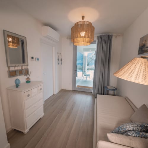 Modernes Schlafzimmer im Verdolivo B&B in Sale Marasino mit Holzböden, weißen Möbeln und Seeblick durch Glastüren