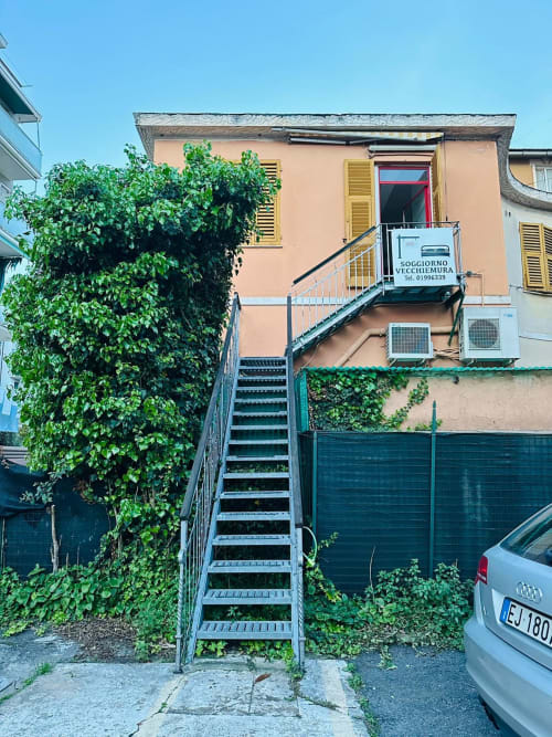 Ingresso del Vecchie Mura BnB a Varazze con scalinata ricoperta d'edera e edificio color pesca