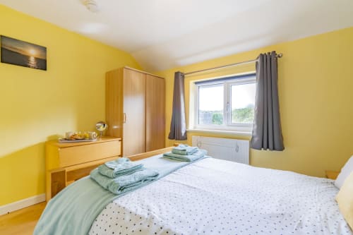 Serene master bedroom at Meadow Rise, a cozy Cornish holiday property tucked away in the picturesque village of St Columb Major, Cornwall. Relax and unwind in this spacious retreat adorned with tasteful decor and plush furnishings. Enjoy a peaceful night's sleep amidst the tranquil ambiance of the Cornish countryside, promising a rejuvenating stay for guests.