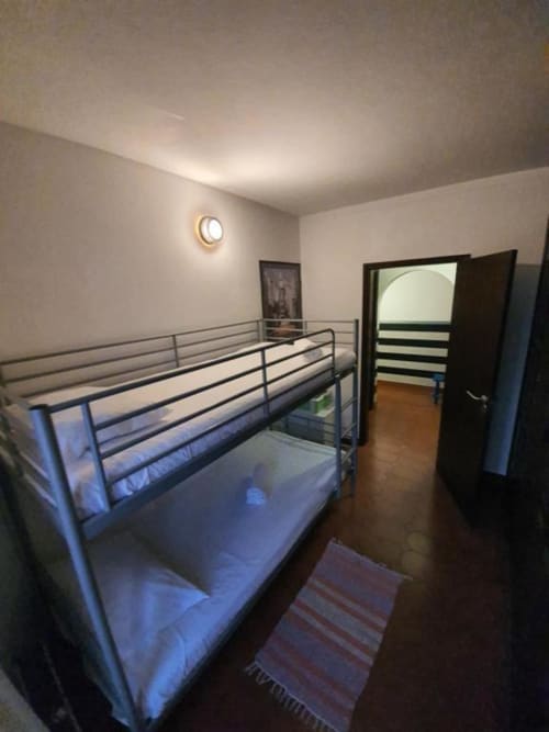 Economy bunk bed room at Ocean View Lagos hostel in Portugal with metal frame beds, wall clock, and mountain view door