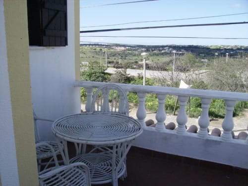 Balcony terrace at Ocean View Lagos hostel with white rattan chairs overlooking rolling hills and valley landscape in Lagos,