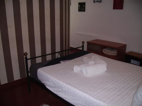 Habitación doble en el hostal Ocean View Lagos en Portugal con cama de marco metálico, sábanas blancas, papel tapiz a rayas y madera oscura