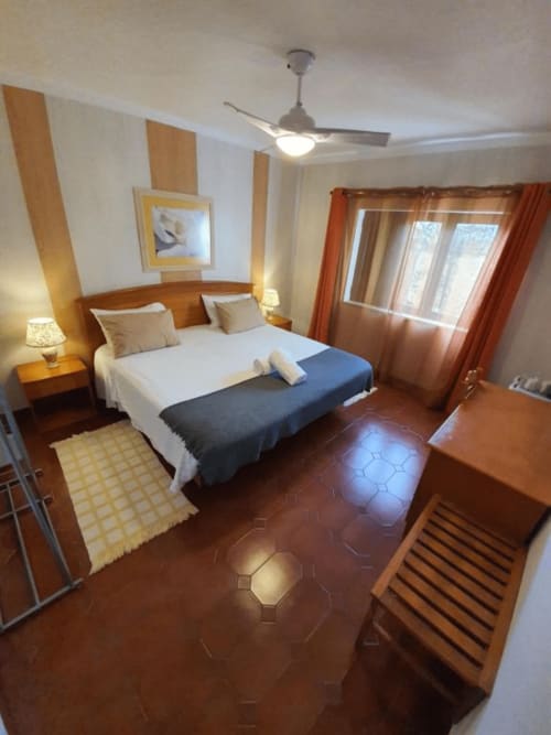 Double room at Ocean View Lagos hostel in Portugal with queen bed, wooden furniture, fan, and terracotta tile flooring