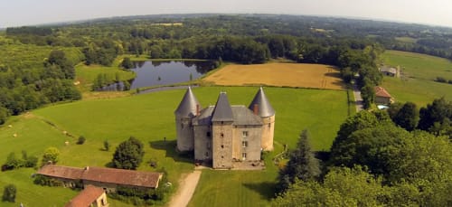 Château de Brie, un château de pierre aux tourelles entouré de prairies verdoyantes et d'un étang à Champagnac-la-Rivière, en France