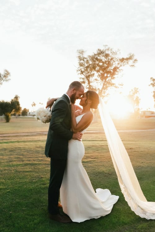 Les mariés s'embrassent au coucher de soleil dans un champ du Château De Brie, un lieu de mariage romantique en Champagne.