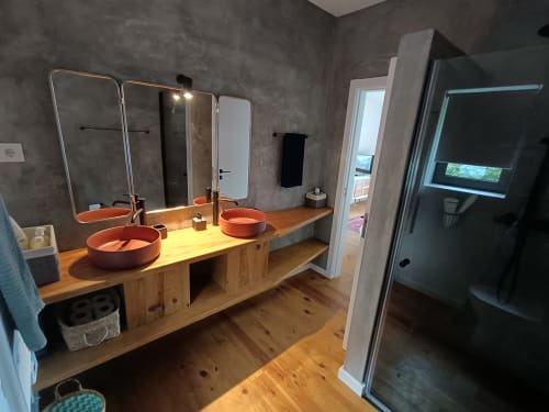 Banheiro moderno com dupla bancada em madeira, pias em terracota, espelhos com iluminação e box de vidro em Quinta do