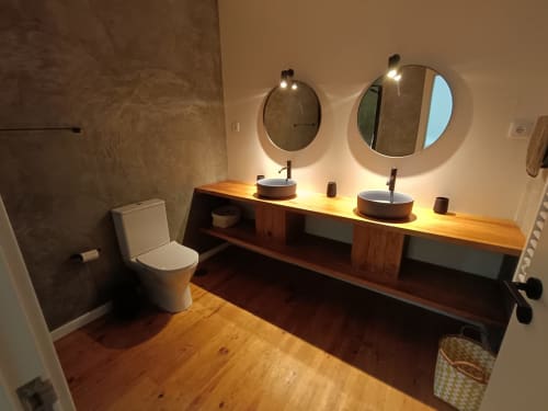Banheiro moderno na quinta com pias duplas, espelhos redondos, móvel de madeira e piso em madeira