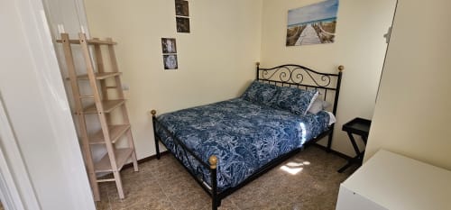 Quarto em Sunao Nazaré com cama queen, cabeceira de ferro forjado, prateleira de madeira e arte decorativa na parede em Nazaré, Portugal