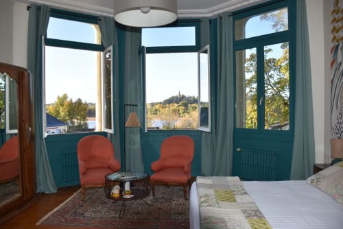 Chambre avec baies teintées turquoise, chaises rouges et vue sur la vallée de la Loire au Domaine de l'Oie Rouge près d'Angers