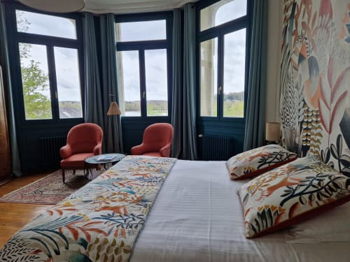 Camélia bedroom at Domaine de l'Oie Rouge with Loire river views, floral bedding, red chairs, and large windows overlooking