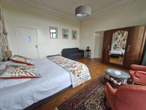 Spacious Camélia bedroom at Domaine de l'Oie Rouge with queen bed, sitting area, and wooden wardrobe overlooking Loire Valley