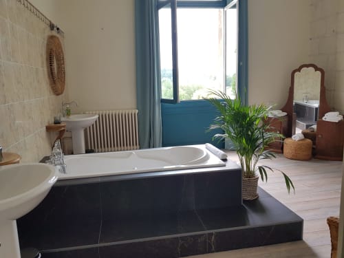 Luxurious black marble bathtub in Camélia room at Domaine de l'Oie Rouge, Gennes-Val-de-Loire, with river views through blue