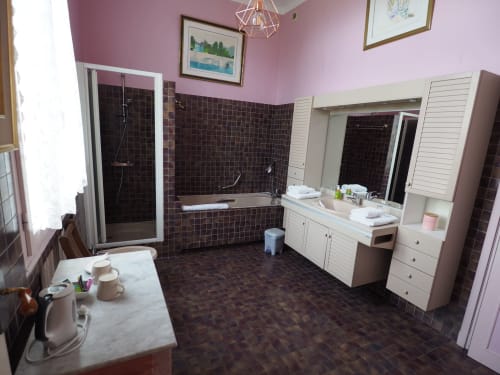 Spacious en-suite bathroom with pink walls, dark tile, dual vanity, bathtub and shower at Domaine de l'Oie Rouge