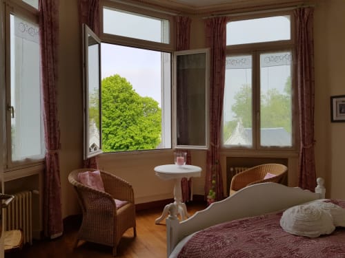 Romance room at Domaine de l'Oie Rouge with wicker chairs, garden views through French windows, and burgundy décor