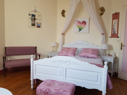 Romantic bedroom with white canopy bed, pink bedding, and garden views at Domaine de l'Oie Rouge in Gennes-Val-de-Loire