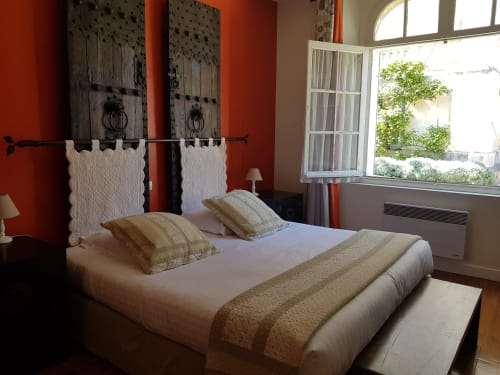 Santal bedroom at Domaine de l'Oie Rouge with queen bed, red walls, antique wooden headboard, garden view windows