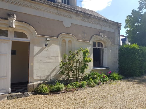 Stone facade of Domaine de l'Oie Rouge guesthouse in Gennes-Val-de-Loire with arched windows and garden courtyard