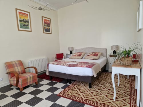 Coriandre bedroom at Domaine de l'Oie Rouge with queen bed, plaid chair, and checkered floor in Gennes-Val-de-Loire
