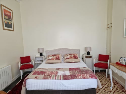 Coriandre bedroom at Domaine de l'Oie Rouge with red patterned bedding, twin lamps, and garden view in Gennes-Val-de-Loire