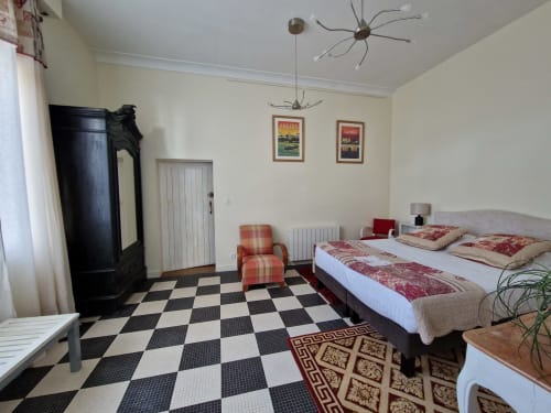 Coriandre bedroom at Domaine de l'Oie Rouge with checkered floor, queen bed, and vintage black wardrobe in