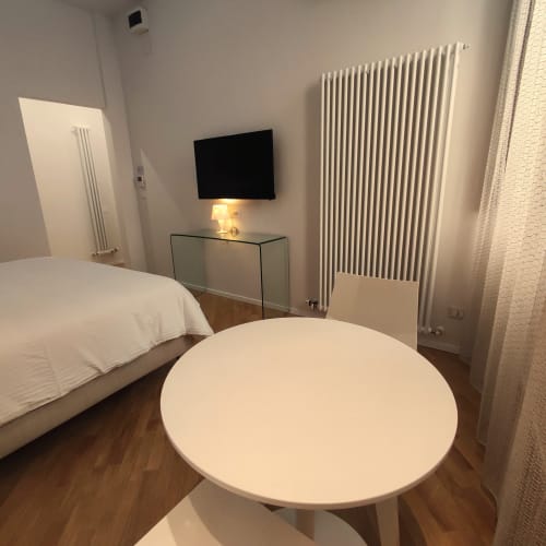 Modern Junior Suite Superior bedroom at Stella CasaBono hotel in Sulmona with flat-screen TV, round white table, and