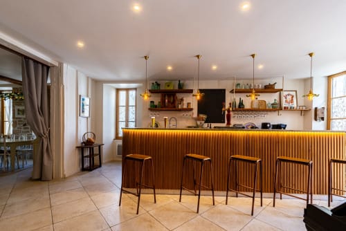 Modern bar and lounge area at La Maison George hotel in Flavigny sur Ozerain with wooden counter, bar stools, and ambient