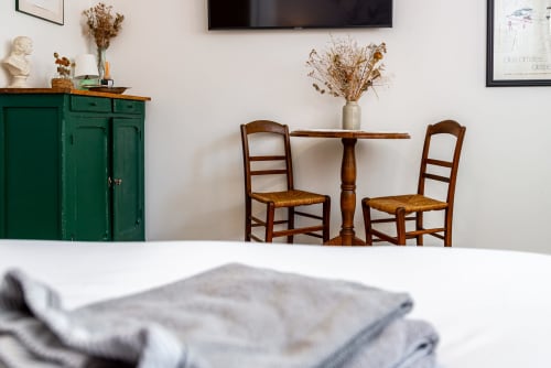 Logis Camille dining area at La Maison George with wooden table, rush chairs, and green vintage cabinet