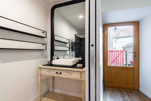 Modern bathroom in Logis Camille at La Maison George with vessel sink, black mirror, and wooden vanity