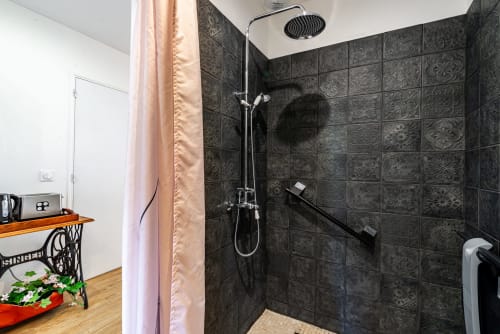 Modern shower with dark patterned tiles at La Maison George's Logis Camille apartment in Flavigny sur Ozerain